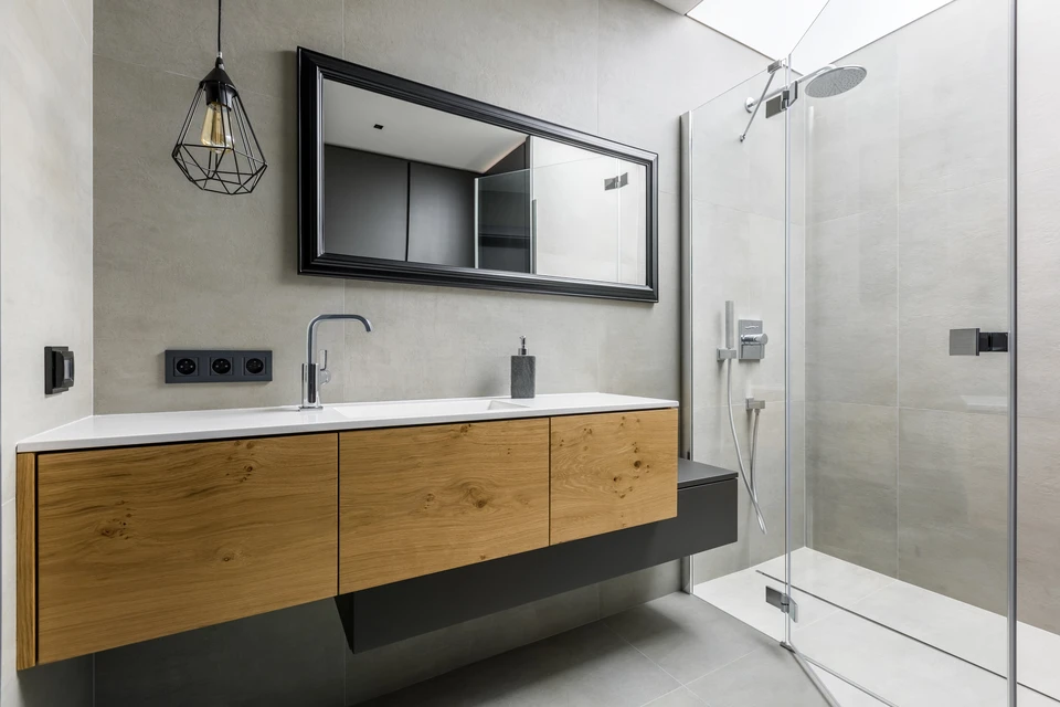 Salle de bains moderne et grise avec douche de plain-pied, miroir et lavabo sur le plan de travail