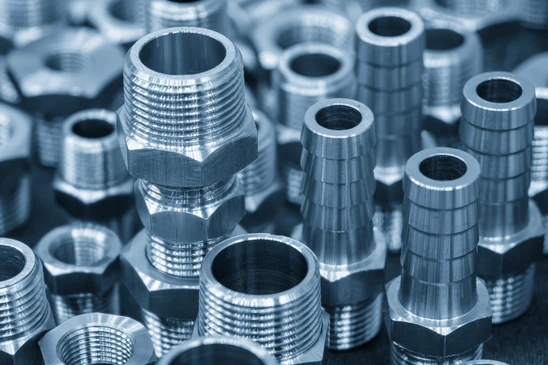 Assemblage de composants de plomberie dispos&eacute;s sur fond blanc&nbsp;: raccords en PVC blanc coud&eacute;s, coudes en cuivre, raccords laiton, bonde d'&eacute;vacuation chrom&eacute;e avec grille, joint d'&eacute;tanch&eacute;it&eacute; blanc, vis de fixation