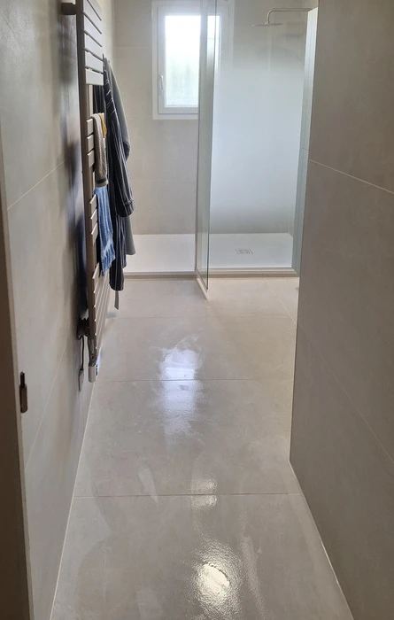 Salle de bain luxueuse avec baignoire d'angle à jets, douche à l'italienne avec paroi vitrée, banquette rembourrée blanche