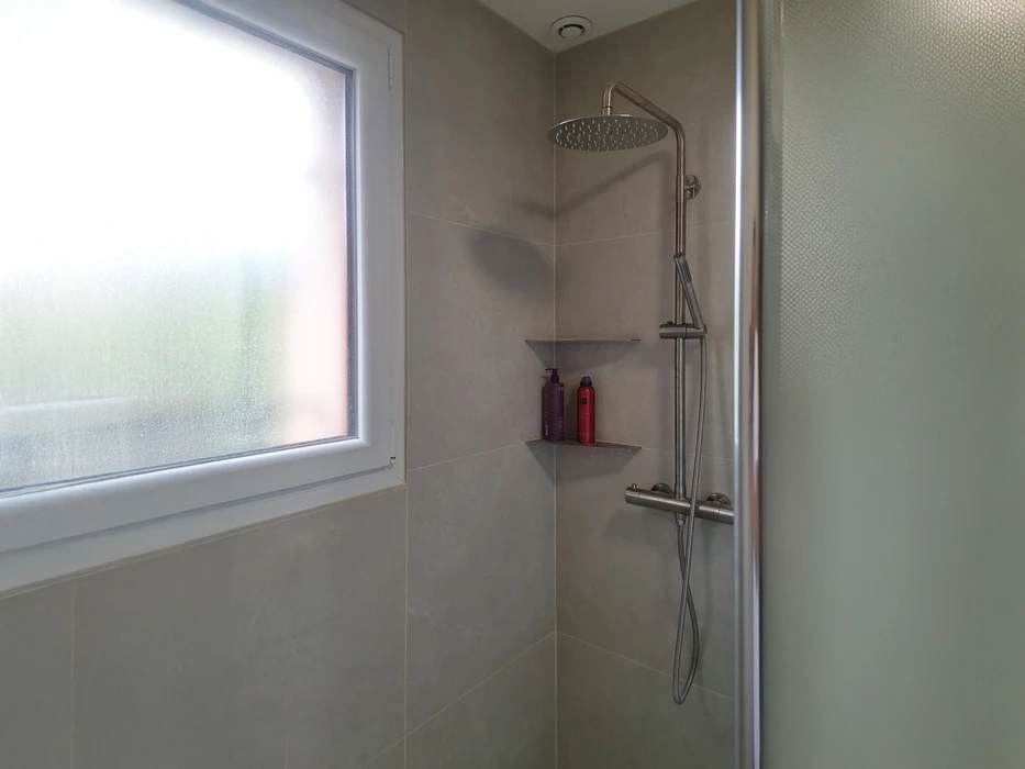 Salle de bain moderne haut de gamme avec baignoire encastrée, double vasque sur plan de travail suspendu, WC et sèche-serviettes chromé