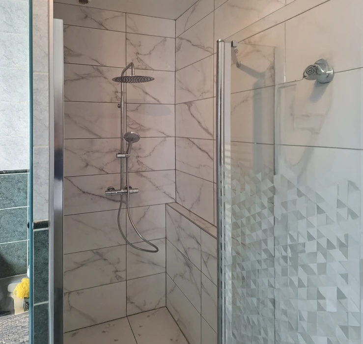 Salle de bain moderne haut de gamme avec douche à l'italienne vitrée, meuble vasque suspendu en bois texturé, miroir rétroéclairé LED